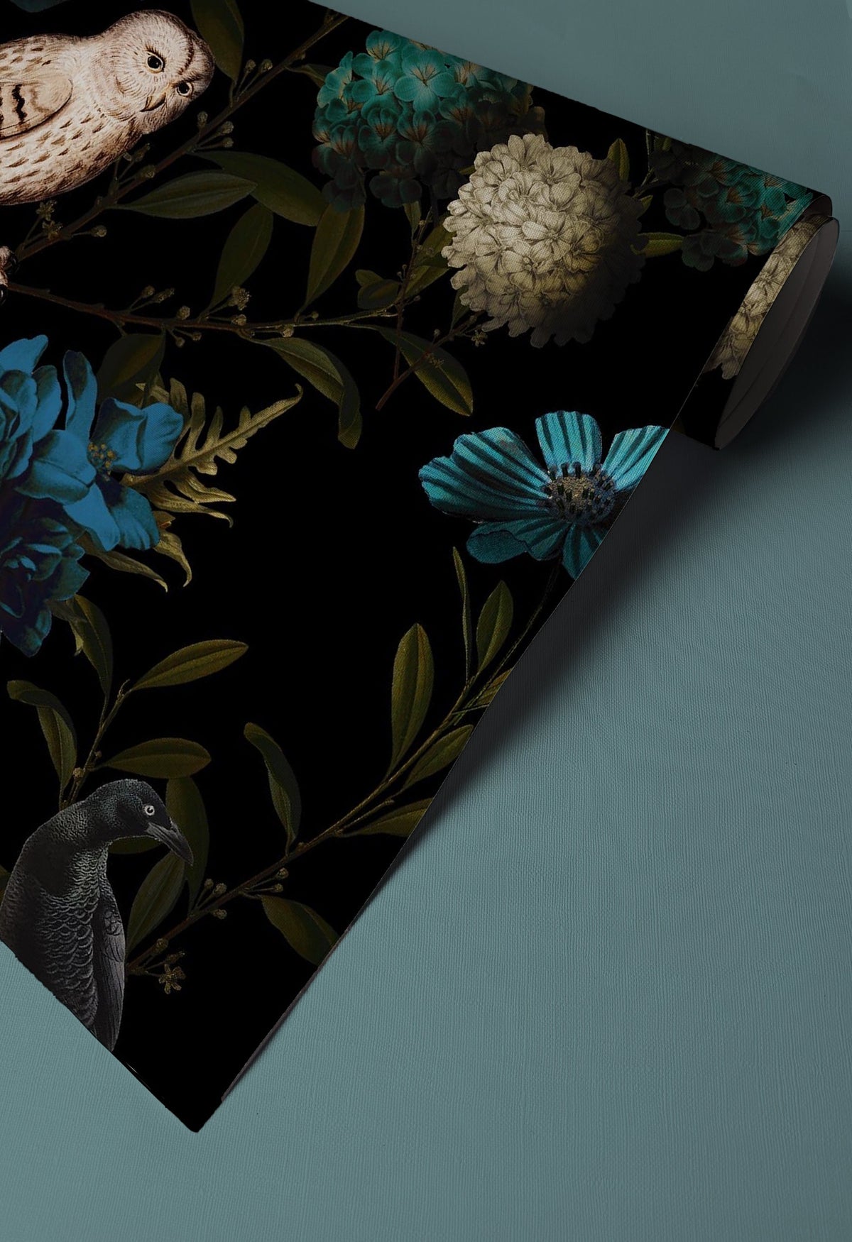 Dark owl and floral wallpaper with teal blue flowers, butterflies, birds and deep green foliage on a black background up close.