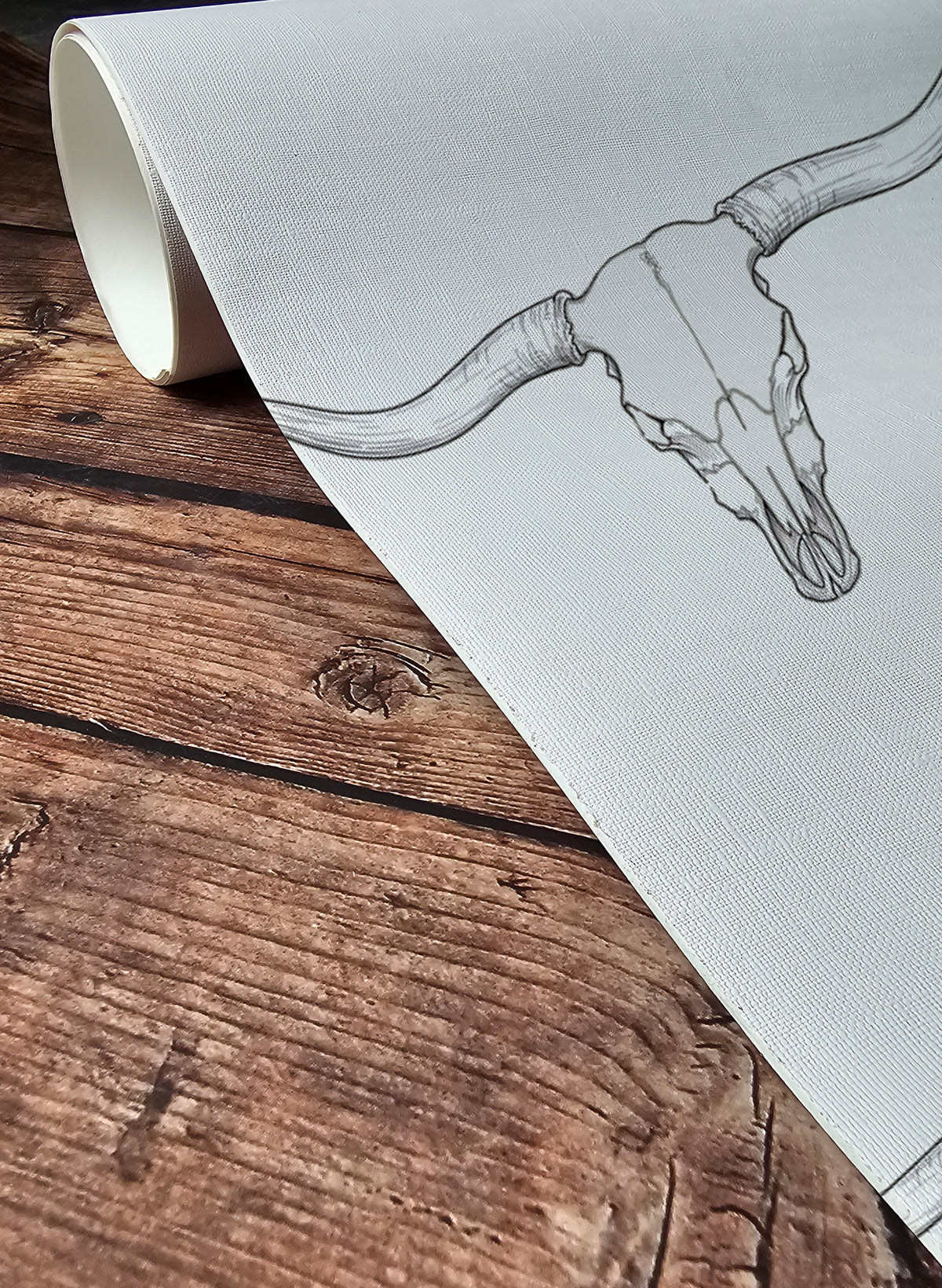 Roll of wallpaper with a bull skull design on a wooden surface