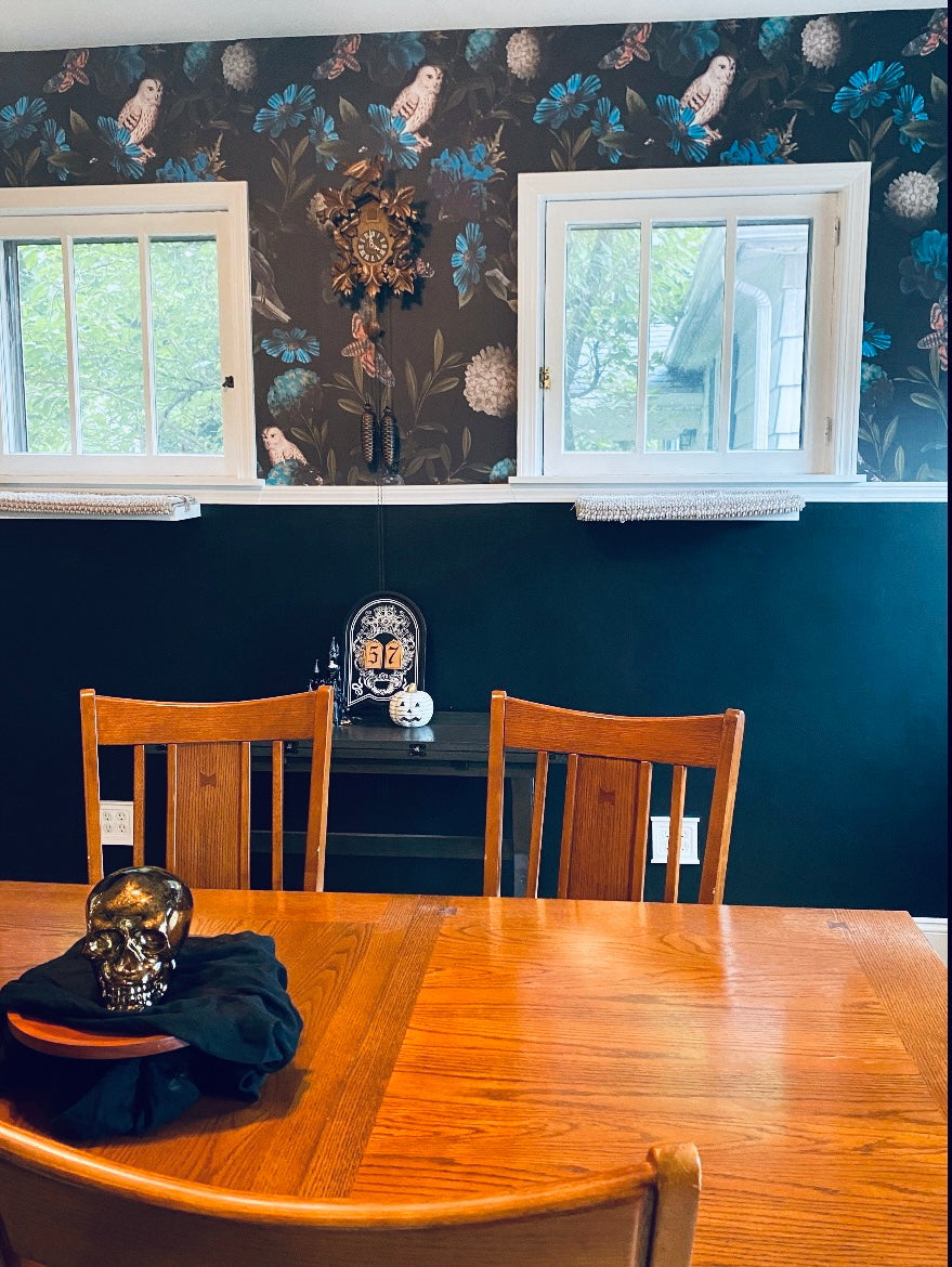 Dark owl and floral wallpaper with teal blue flowers, butterflies, birds and deep green foliage on a black background in dining room.