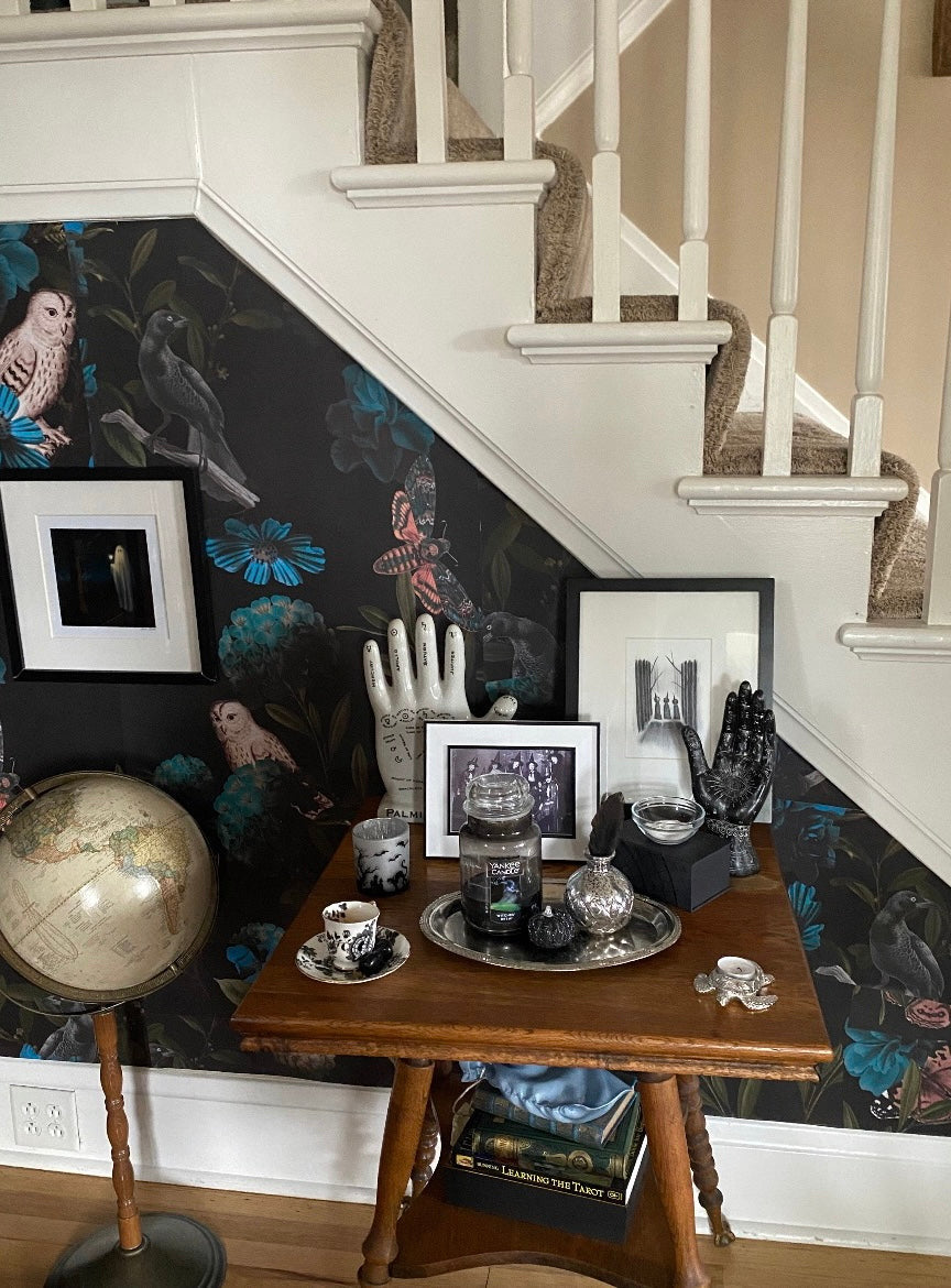 Dark owl and floral wallpaper with teal blue flowers, butterflies, birds and deep green foliage on a black background in entryway.