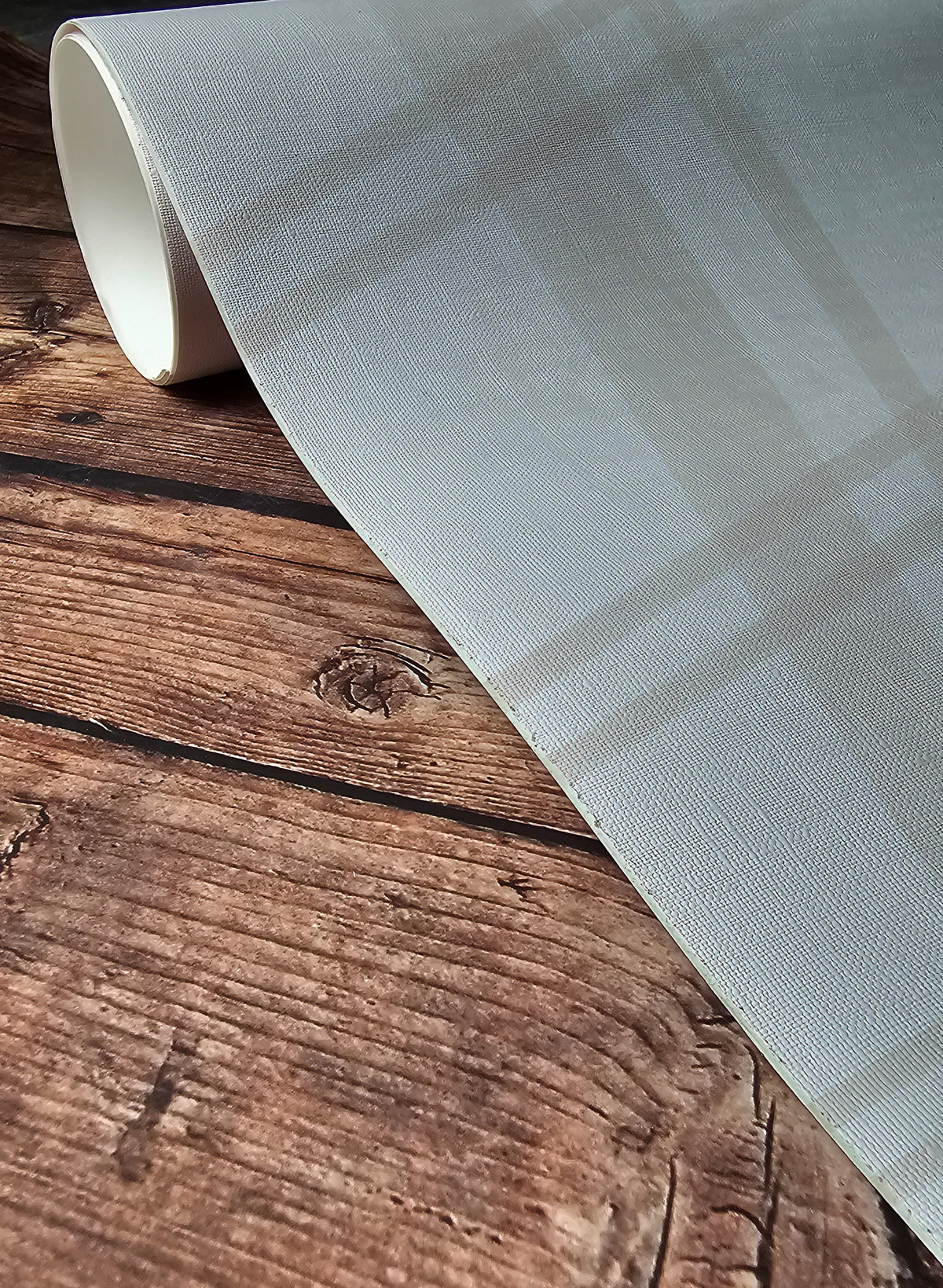 Neutral plaid wallpaper featuring soft beige and blush pink lines forming a classic tartan pattern on a warm cream background on a roll