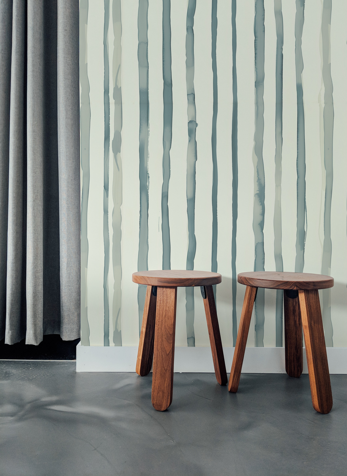 Soft watercolor stripe wallpaper with vertical blue green stripes on a warm neutral background.