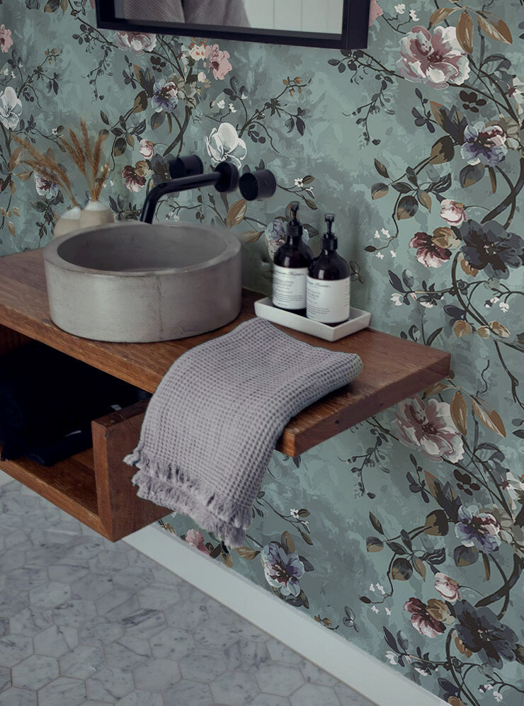 Vintage floral wallpaper with soft pink, cream and purple flowers, dark trailing branches and muted foliage on a dusty sage green background in bathroom.