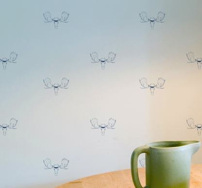 Minimal wallpaper with repeating moose head illustration wearing a top hat, subtle whimsical peel and stick wallpaper pattern on wall