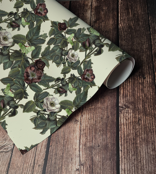Luna Moth wallpaper with pale green moths, dusty mauve and cream roses, and deep green foliage on a warm ivory background up close