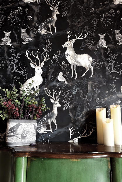 Dark woodland wallpaper featuring graceful deer, owls, and birds among twisting forest branches and soft botanical details on a deep moody background on wall