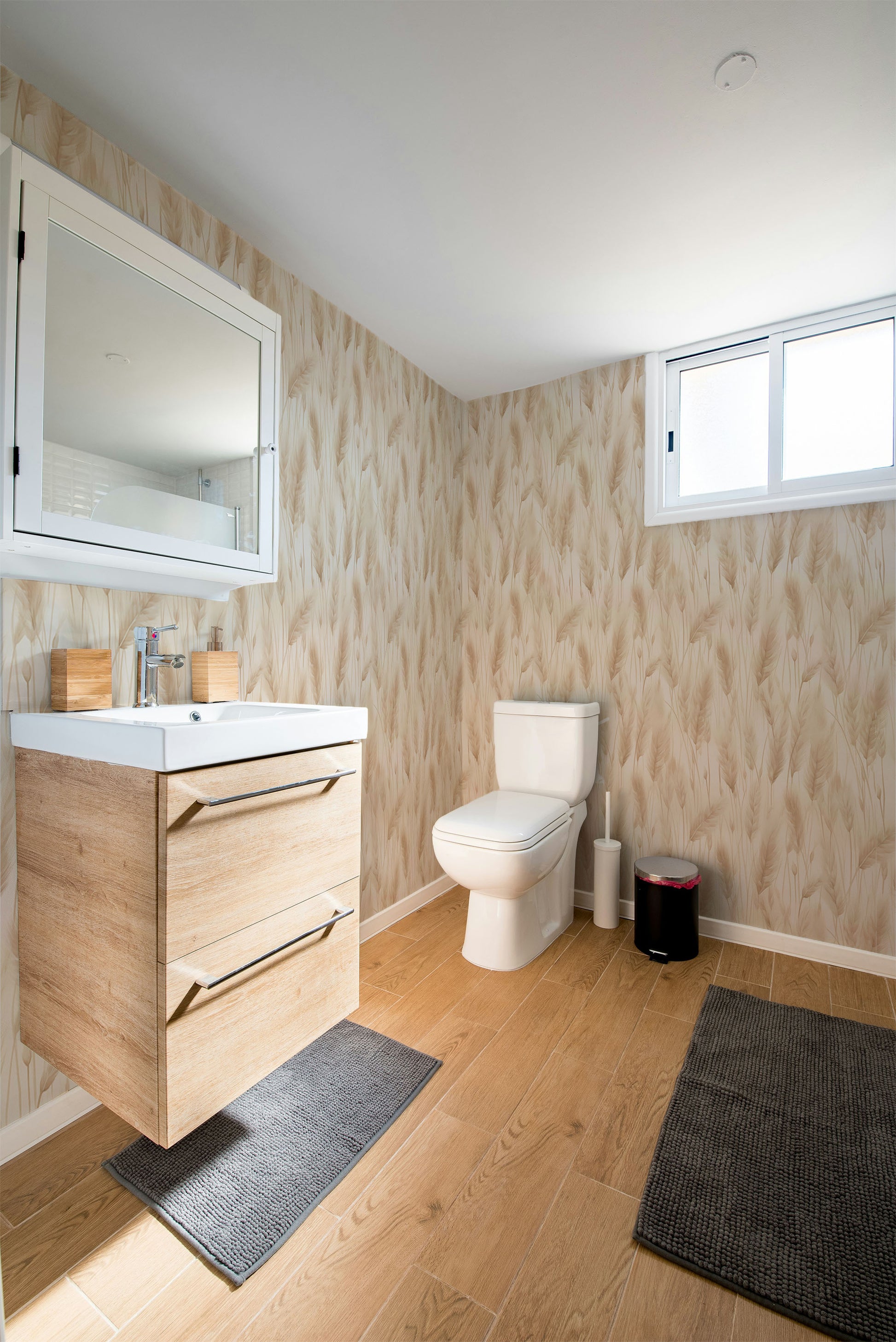 Neutral botanical wallpaper featuring soft pampas grass plumes and dried meadow grasses in warm ivory, cream, and sandy beige tones on a light background in bathroom