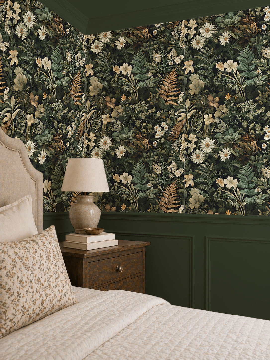 Dark botanical wallpaper featuring lush forest foliage, cream wildflowers, daisies, and ferns on a deep green background, creating a moody cottagecore bedroom accent wall.
