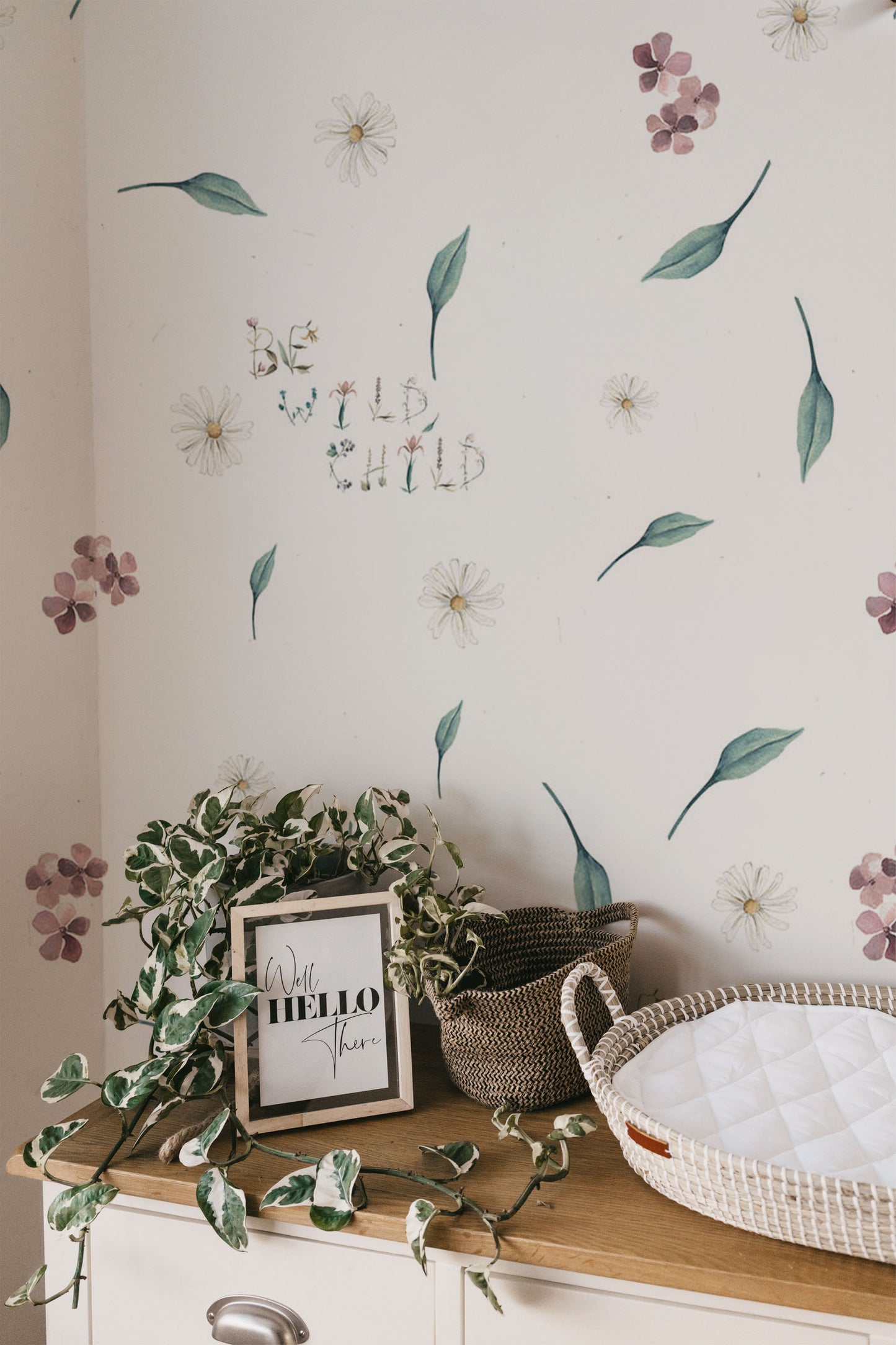 Soft floral nursery wallpaper with delicate wildflowers greenery and whimsical be wild child lettering on a neutral background in a cottagecore style