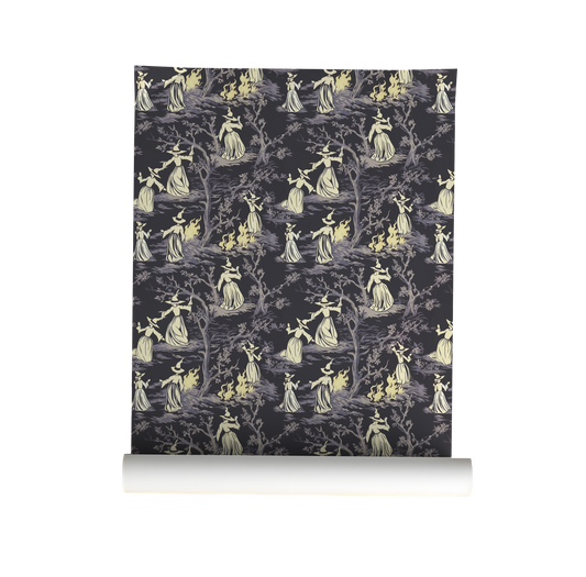Moody peel-and-stick wallpaper sample featuring a witchy toile pattern with cream-cloaked figures, twisted gray trees, and glowing bonfire details on a deep charcoal background on roll