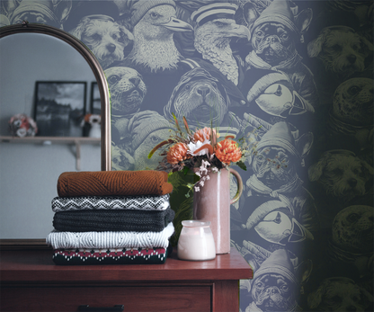 Blue peel-and-stick wallpaper sample featuring detailed illustrated animal portraits, including puffins, eagles, pugs, ducks, and sea otters wearing knit hats and sailor caps in a whimsical nautical style in room