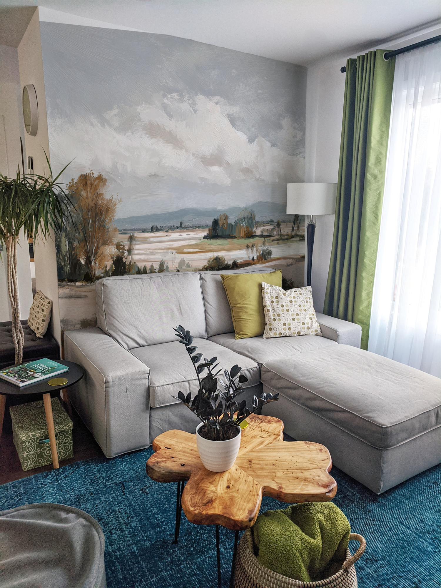Modern living room with a gray sectional sofa, and landscape wall mural