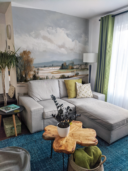 Modern living room with a gray sectional sofa, and landscape wall mural