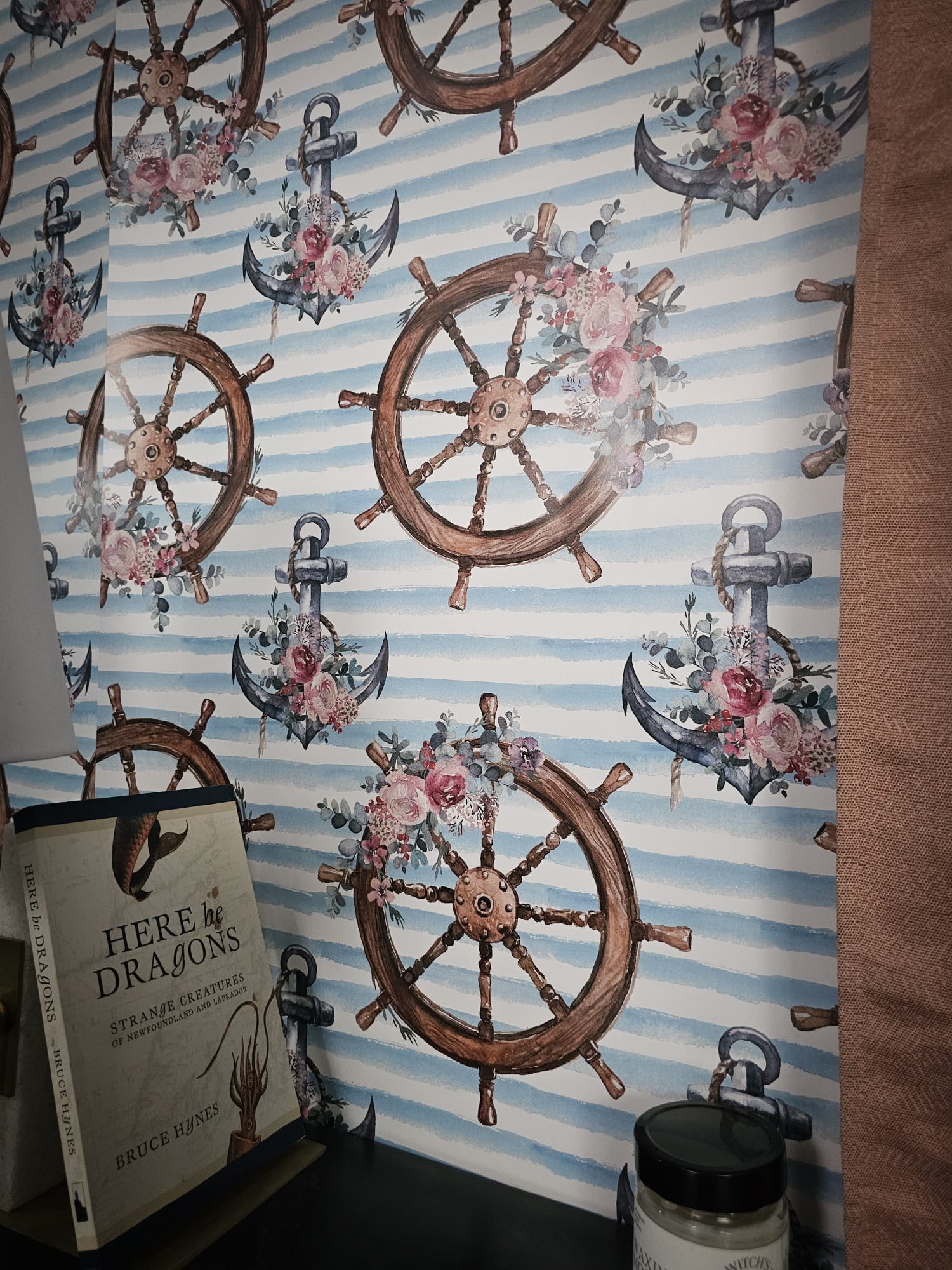 Wallpaper with nautical designs including ship wheels, anchors, and flowers on a striped background.